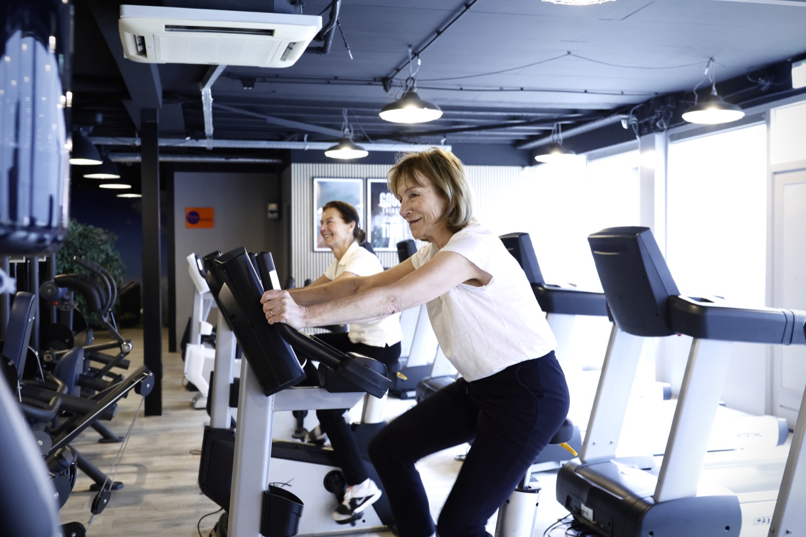 Twee deelnemers trainen samen op de fiets bij FitFever